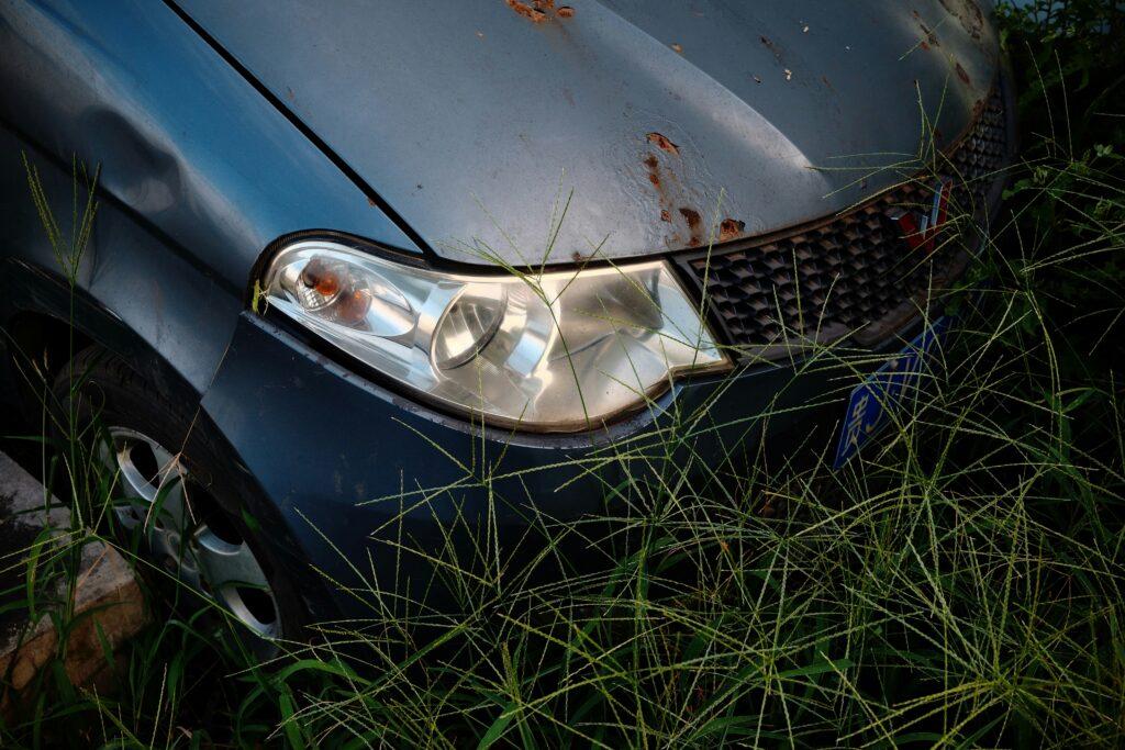 A car parked on a grassy area, surrounded by green grass and a clear sky in the background.