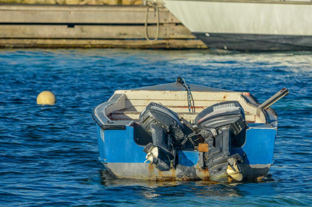 A small boat floating gently on calm water under a clear blue sky.